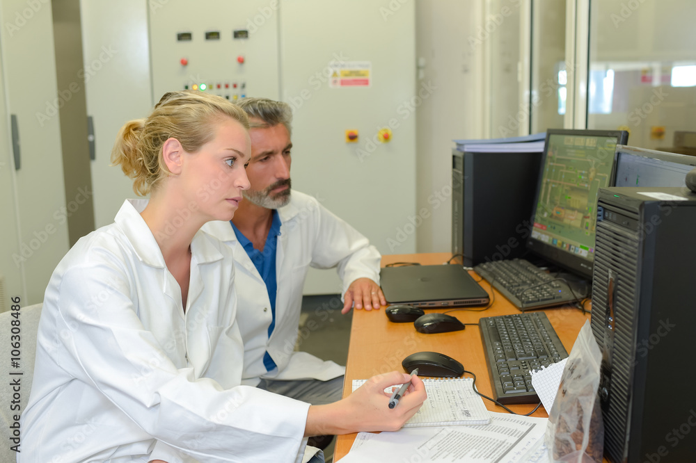 Obraz premium Two technicians looking at computer screen