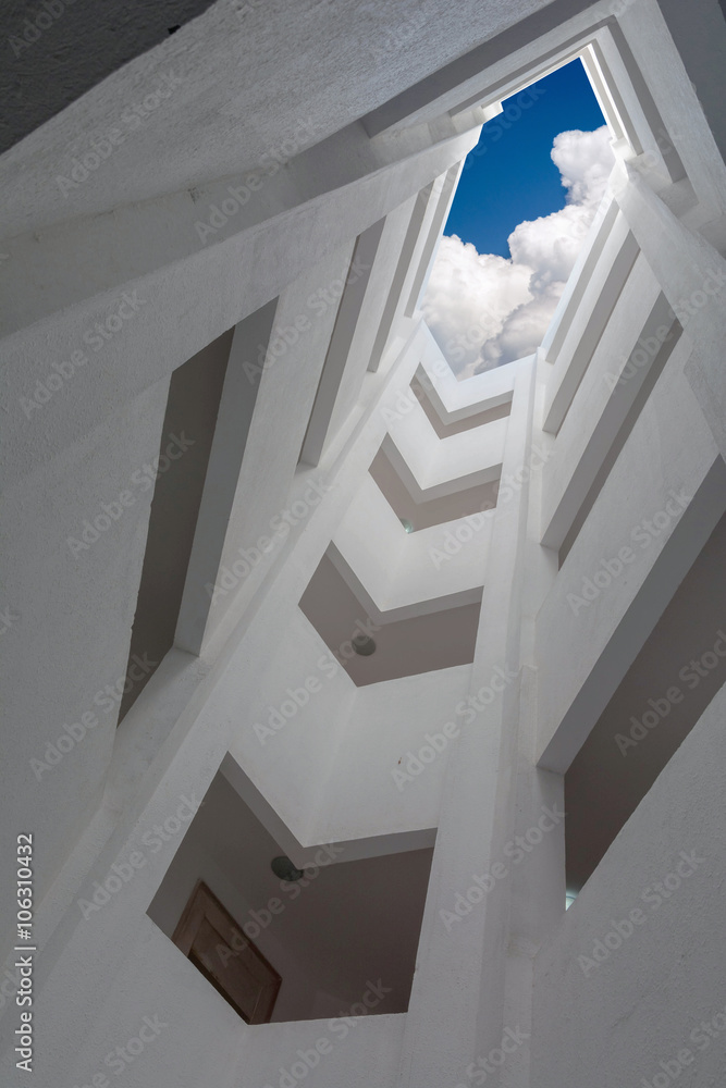 Obraz premium deep atrium gray building overlooking the blue sky with clouds
