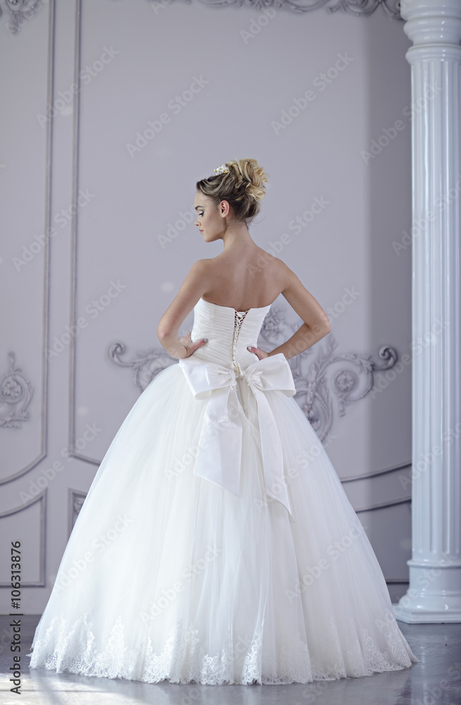 Beauty bride in bridal gown indoors. Beautiful model girl in a white wedding dress. Female portrait of cute lady. Woman with hairstyle Beauty bride in bridal gown indoors. Beautiful model girl in a white wedding dress. Female portrait of cute lady. Woman with hairstyle