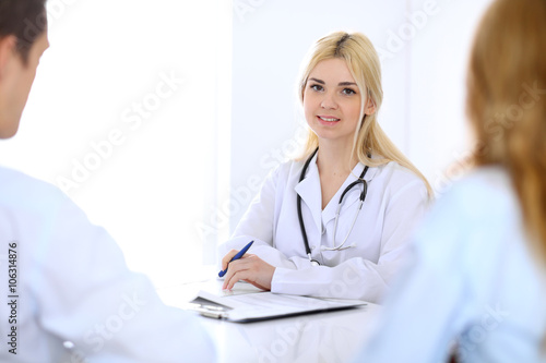 Medical doctor and young couple patients discussing something at the table . Hands close-up © rogerphoto