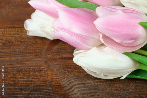 beautiful and fragrant blooming pink and white tulips on a brown wooden background
