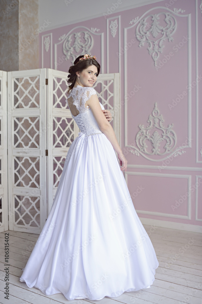 Beauty bride in bridal gown indoors. Beautiful model girl in a white wedding dress. Female portrait of cute lady. Woman with hairstyle Beauty bride in bridal gown indoors. Beautiful model girl in a white wedding dress. Female portrait of cute lady. Woman with hairstyle