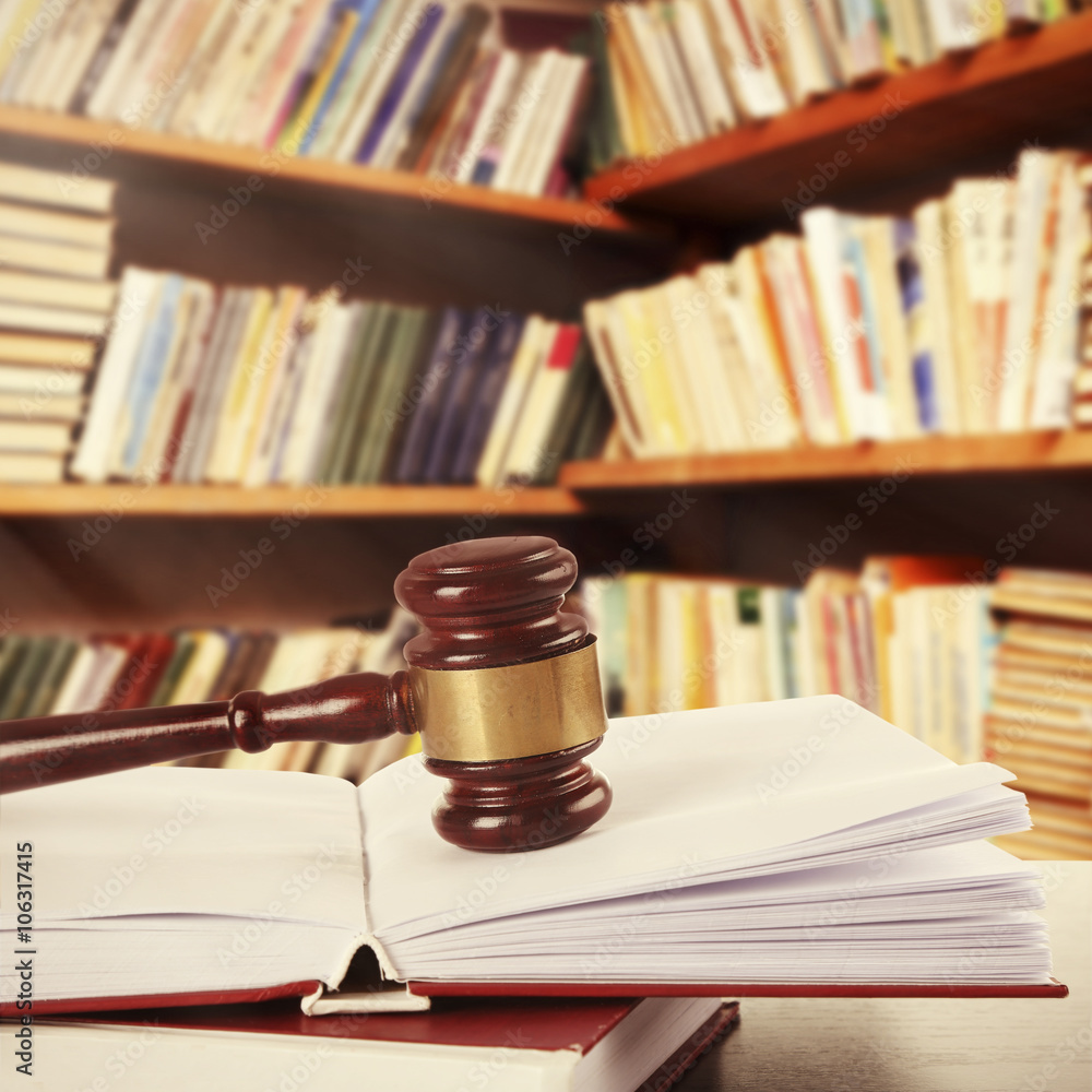Wooden judges gavel lying on law book on table in library Wooden judges gavel lying on law book on table in library
