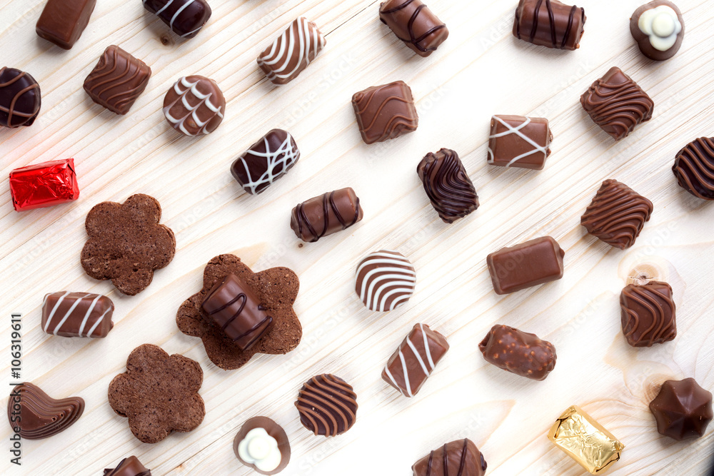 abundance of chocolates on a light wooden background close up, the top view abundance of chocolates on a light wooden background close up, the top view