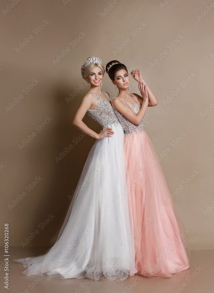 Two fashiom models in wedding silk dress isolated on beige Two fashiom models in wedding silk dress isolated on beige