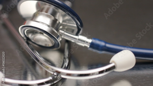 Close up of a medical stethoscope on a rotating reflective metal surface.