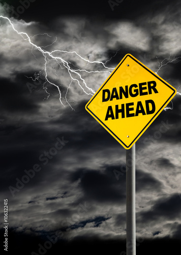 Danger Ahead Sign Against Cloudy and Thunderous Sky