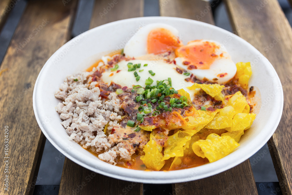 bowl of noodles with vegetables and soft boiled egg on wooden ta