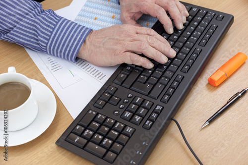 Accountant at his desk using a computer keyboard