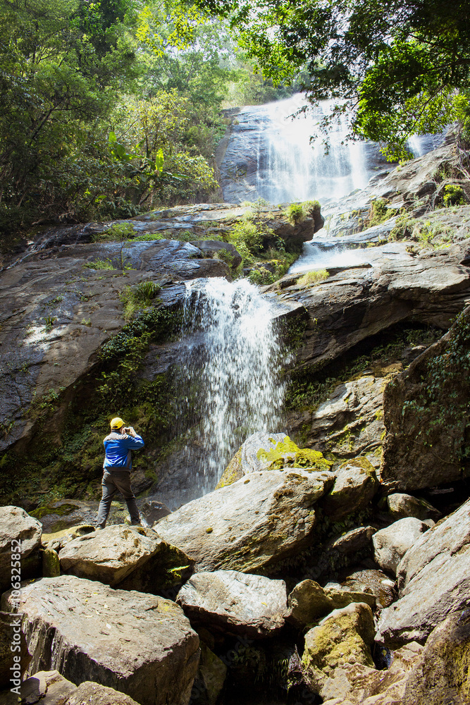 Traveler man taking photo of big waterfall, jungle, Thailand