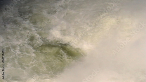 Dynamic close-up of churning white-water rapids swirling with foam below the Pailon del Diablo falls in Ecuador, shot from a high angle.