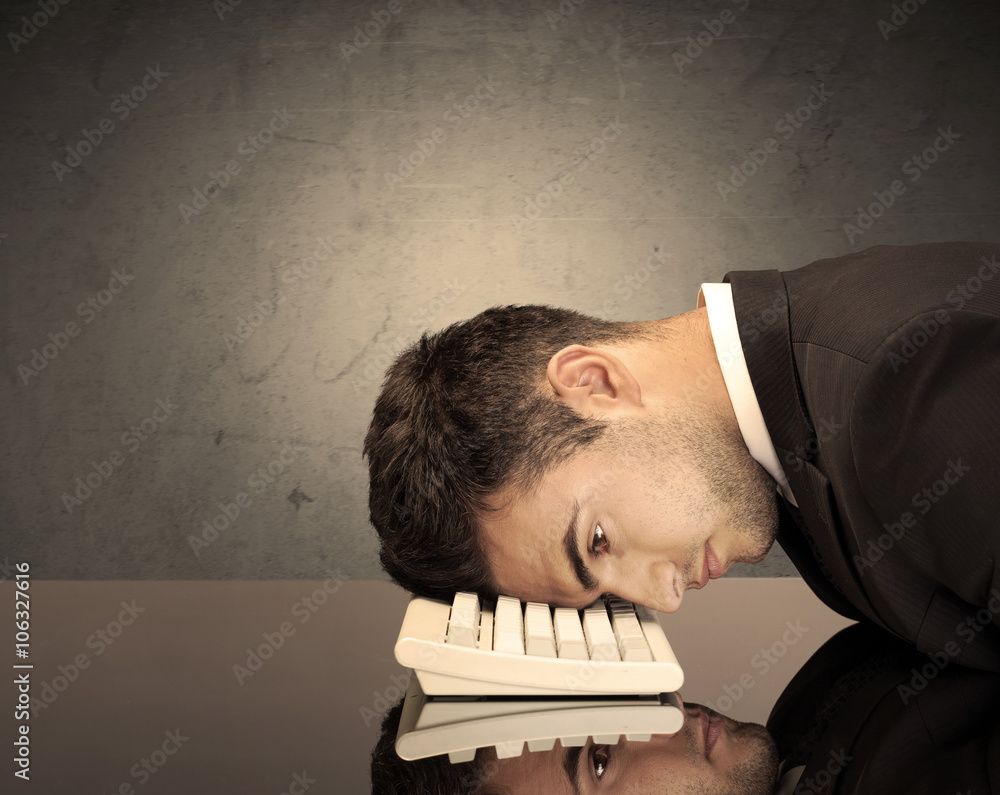 Obraz premium Frustrated businessman's head on keyboard