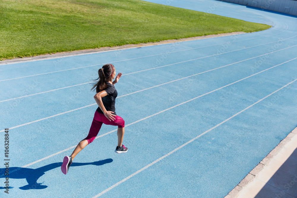 Runner sprinting towards success on run path running athletic track. Goal achievement concept. Female athlete sprinter doing a fast sprint for competition on blue lane at an outdoor field stadium.