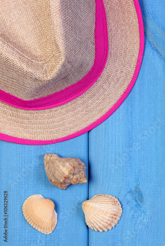 Straw hat and seashells on blue wooden boards, accessories for summer