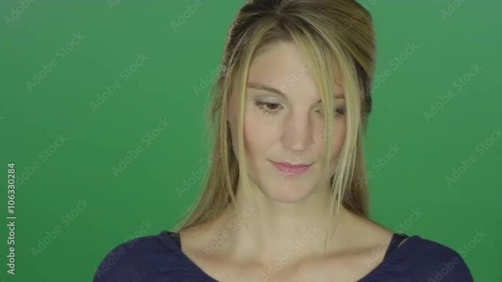 Beautiful woman looking down sadly, on a green screen studio background Beautiful woman looking down sadly, on a green screen studio background