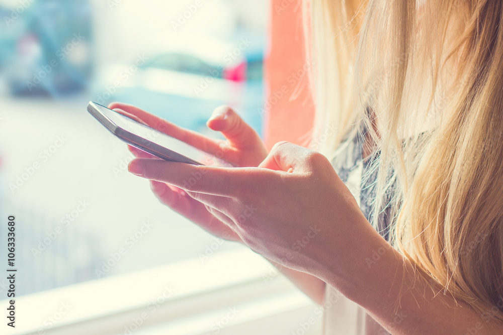 Young blonde hair girl in negligee standing on the window in the morning, typing on smart phone, no face, close up, soft light filter applied Stock Photo | Adobe Stock Young blonde hair girl in negligee standing on the window in the morning, typing on smart phone, no face, close up, soft light filter applied Stock Photo | Adobe Stock