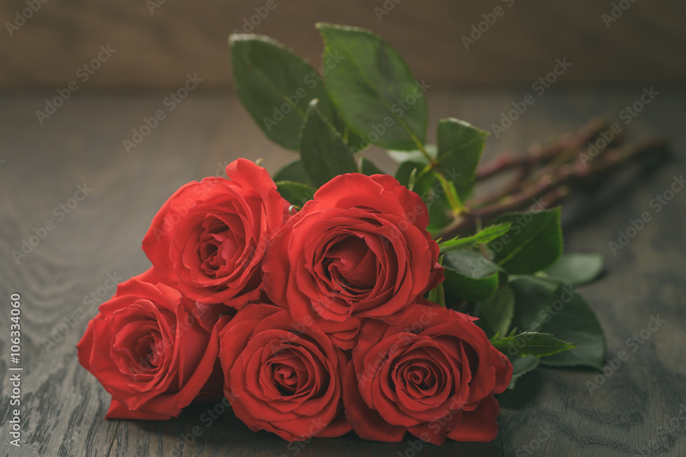 five red roses on wooden table, shallow focus five red roses on wooden table, shallow focus