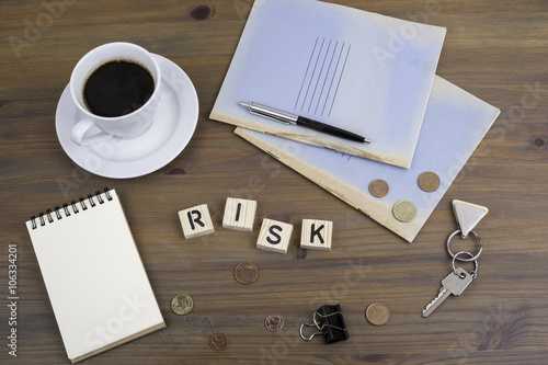Coffe, pen, money and blocknot on a desk and word Risk