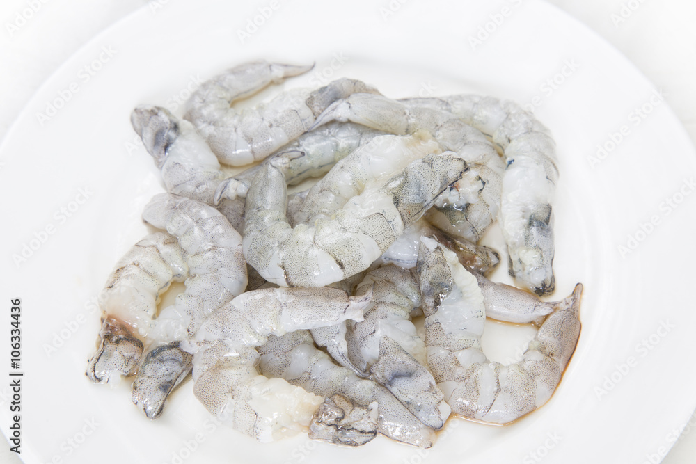 Raw peeled shrimp on white dish on white background. Raw peeled shrimp on white dish on white background.