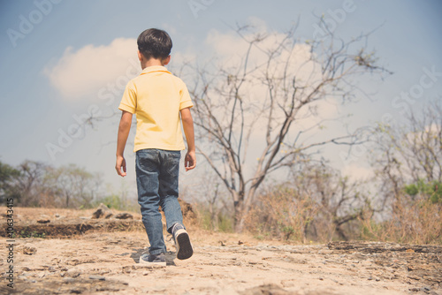 Boy walking on the rocky land.