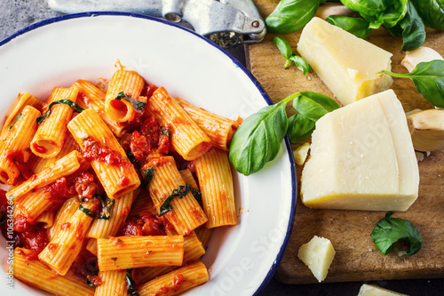 Pasta. Italian and Mediterrannean cuisine. Pasta Rigatoni with tomato sauce basil leaves garlic and parmesan cheese. An old home kitchen with old kitchen utensils. photo