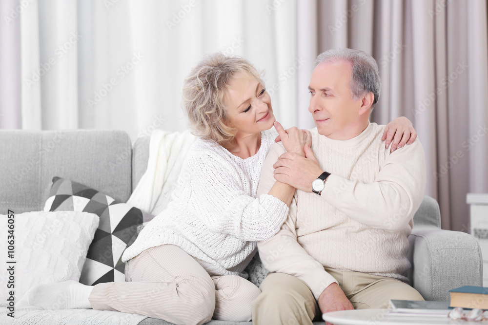 Happy mature couple sitting together on a sofa at home