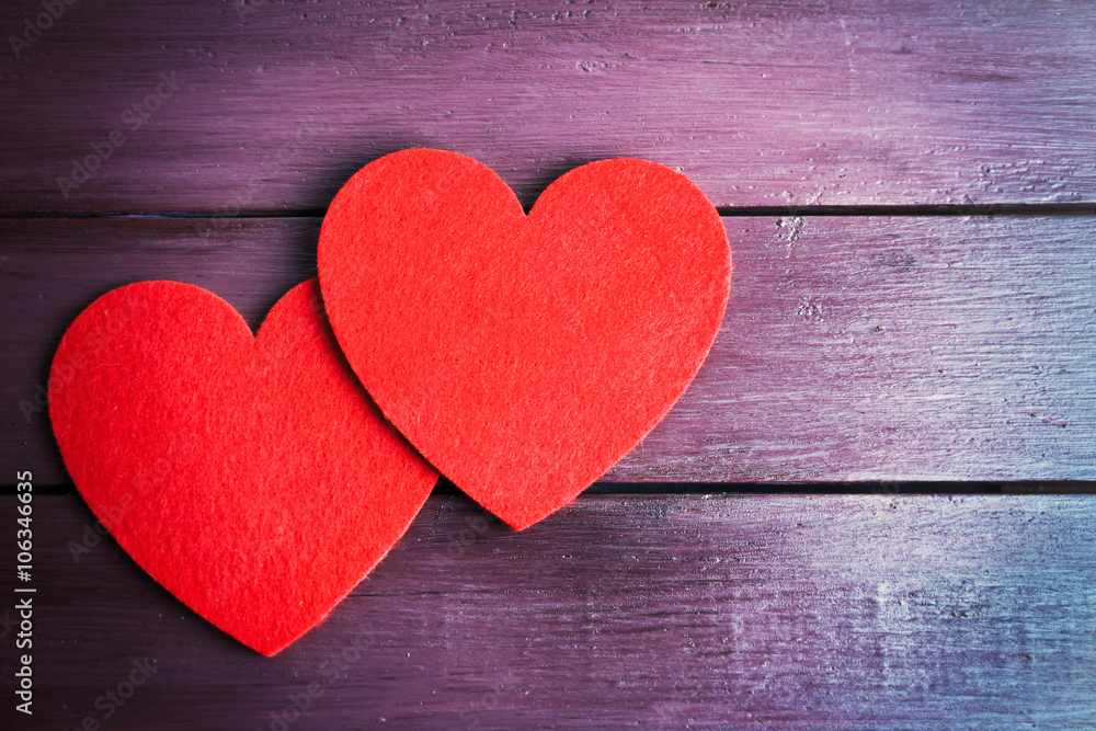 Red felt hearts on purple wooden background Red felt hearts on purple wooden background