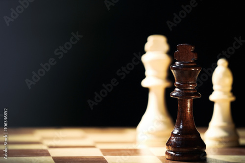 Chess pieces and game board on black background