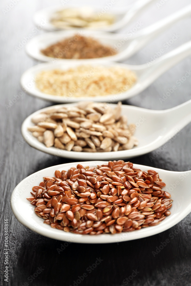 Different kinds of seeds in spoons on wooden table Different kinds of seeds in spoons on wooden table