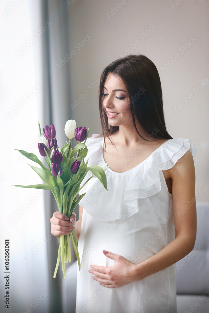 Pregnant woman with beautiful bouquet of tulips in the room Pregnant woman with beautiful bouquet of tulips in the room