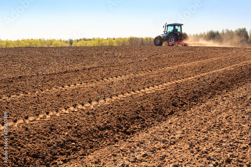 cultivator operates on ploughed field makes dust