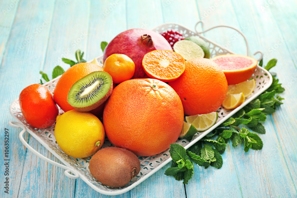 Juicy composition of tropical fruits on a tray on wooden background Juicy composition of tropical fruits on a tray on wooden background