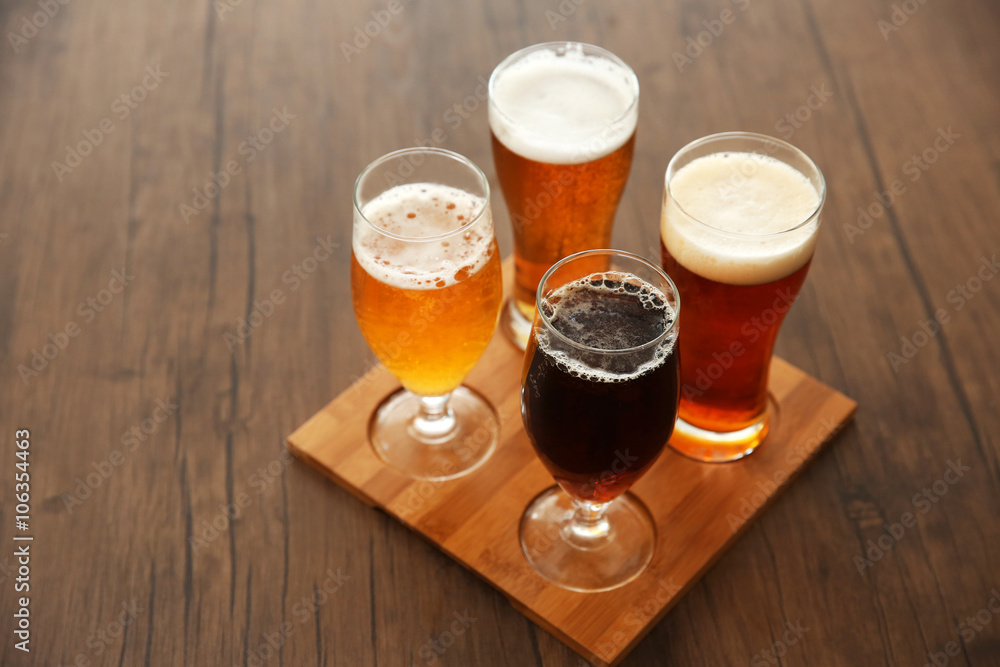 Glasses with different sorts of craft beer on wooden tray Glasses with different sorts of craft beer on wooden tray