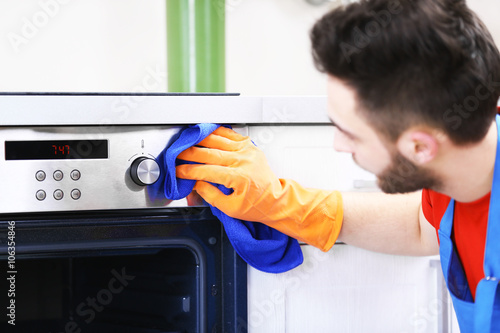Man cleaning oven in the ki...