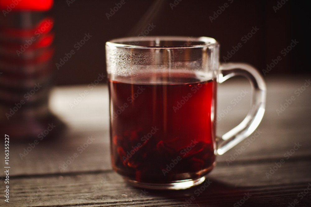 A Cup of hibiscus tea from Sudanese rose with lemon and cinnamon sticks. Brew in teapot on a black wooden background A Cup of hibiscus tea from Sudanese rose with lemon and cinnamon sticks. Brew in teapot on a black wooden background