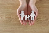 Female hands holding family figure on wooden  background