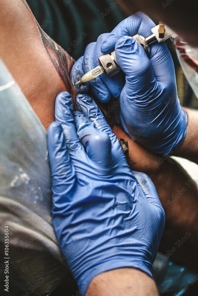 master tattooist does the tattoo in gloves on the hand of the man
