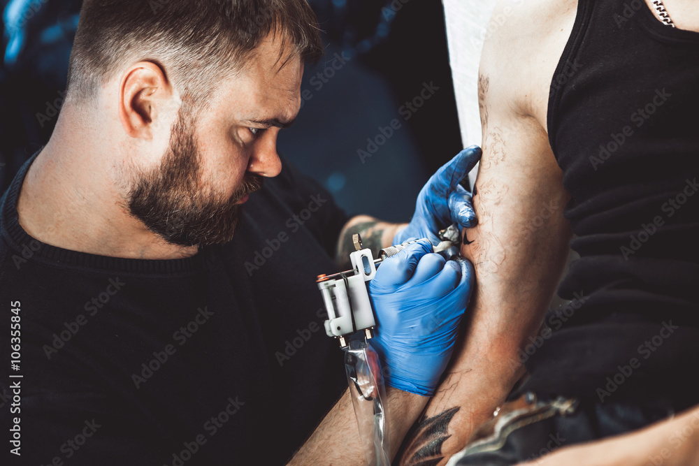 master tattoo artist with a beard makes gloves tattoo on hand men master tattoo artist with a beard makes gloves tattoo on hand men