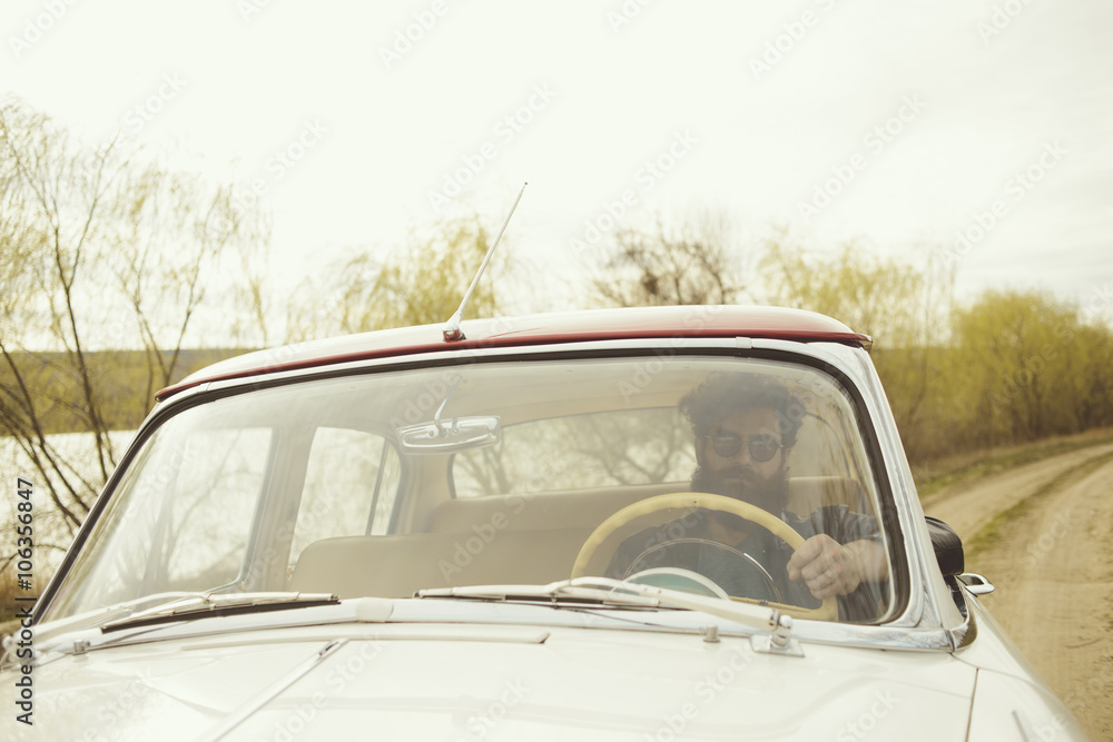 Man with beard driving a retro car