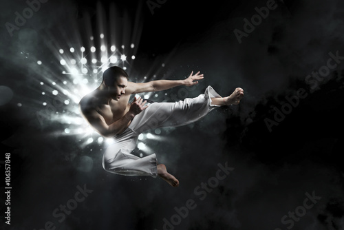 Fototapeta male fighter trains capoeira