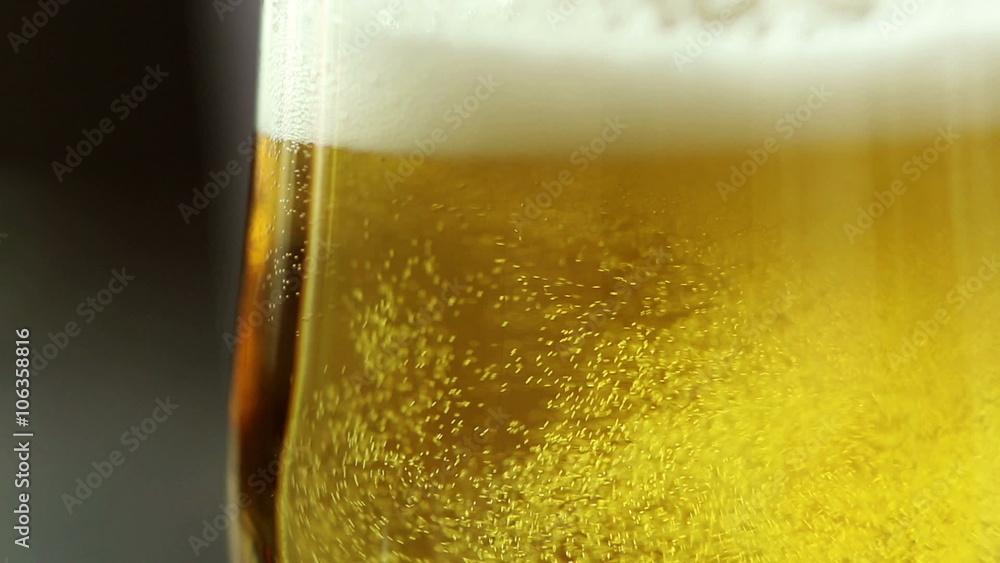Pour beer into a glass on dark wooden table Pour beer into a glass on dark wooden table
