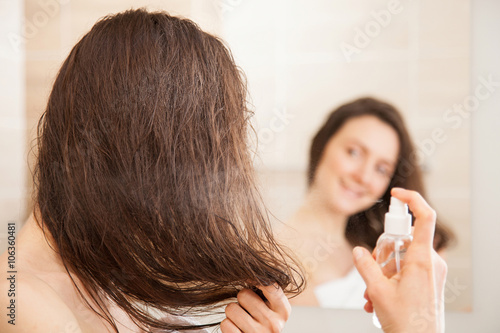 Young woman applying hair spray