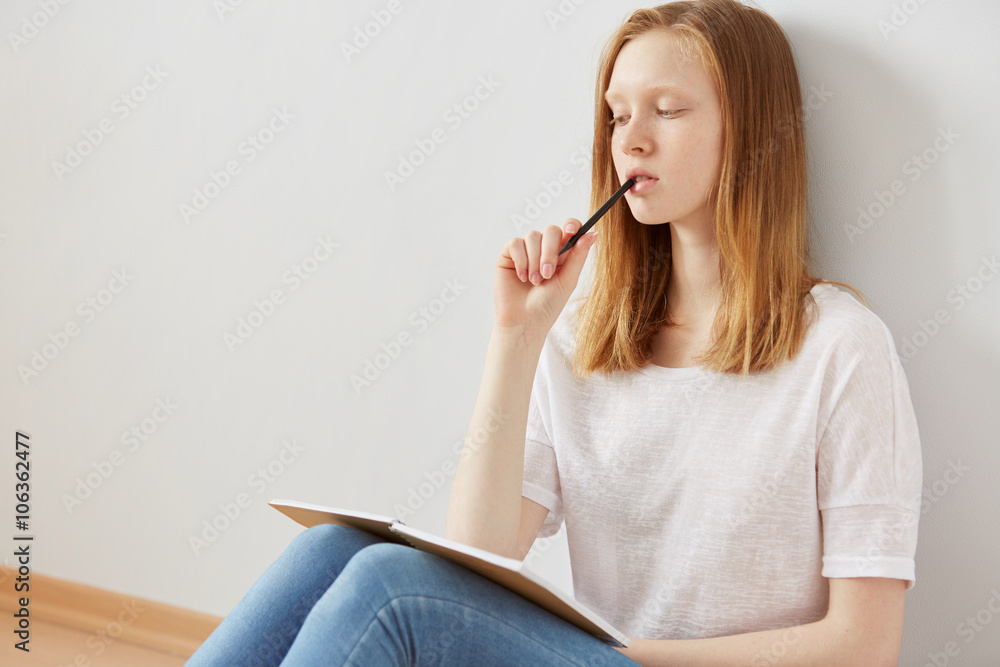 Young girl writing into her notebook in the park