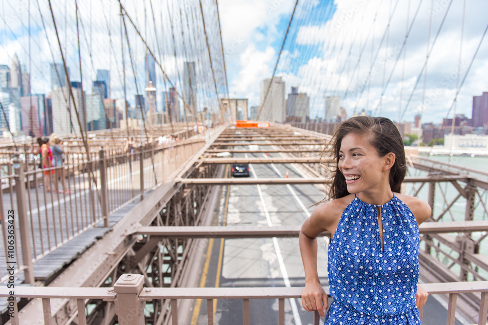 Fototapeta premium Portret pięknej młodej kobiety azjatyckie na Brooklyn bridge, Nowy Jork NYC, Manhattan, USA. Uśmiechnięty turysta w niebieskiej sukience robi letnie podróże w miejskim punkcie orientacyjnym.