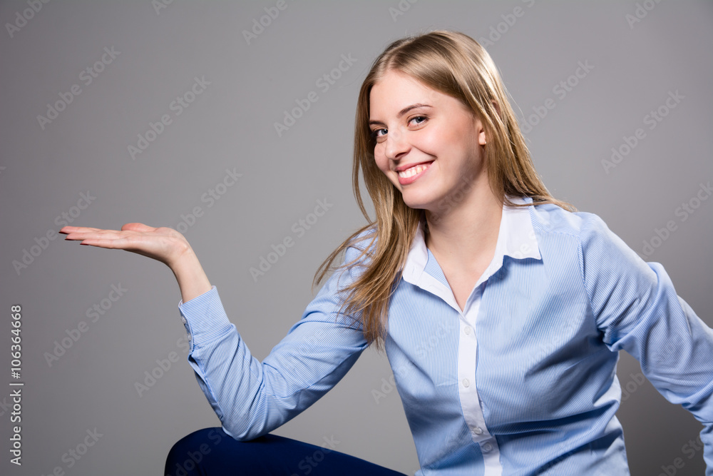 Young woman showing product with open hand palm - excited expression on businesswoman Isolated on gray background. Young woman showing product with open hand palm - excited expression on businesswoman Isolated on gray background.