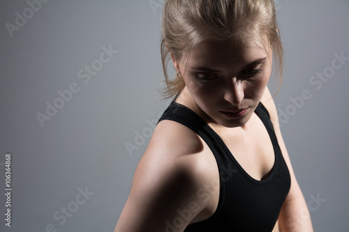 Portrait of a young athletic woman on a gray background.