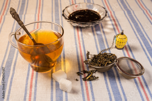 A cup of tea with tea strainer on a table cloth photo