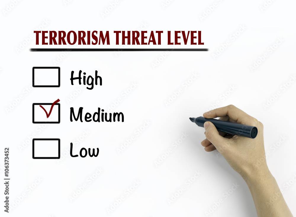Woman's hand writing terrorism threat level on white background Woman's hand writing terrorism threat level on white background