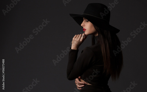 Fashion portrait of young beautiful woman model in casual wear. Black boots, hat and black dress. Copy space.  © lashkhidzetim