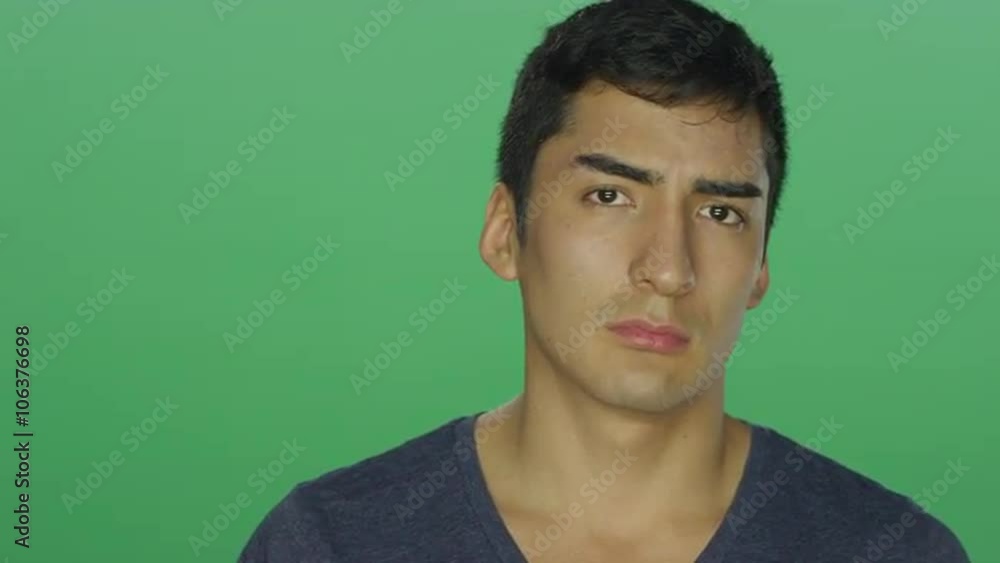 Young man frowns and looks sad, on a green screen studio background Young man frowns and looks sad, on a green screen studio background